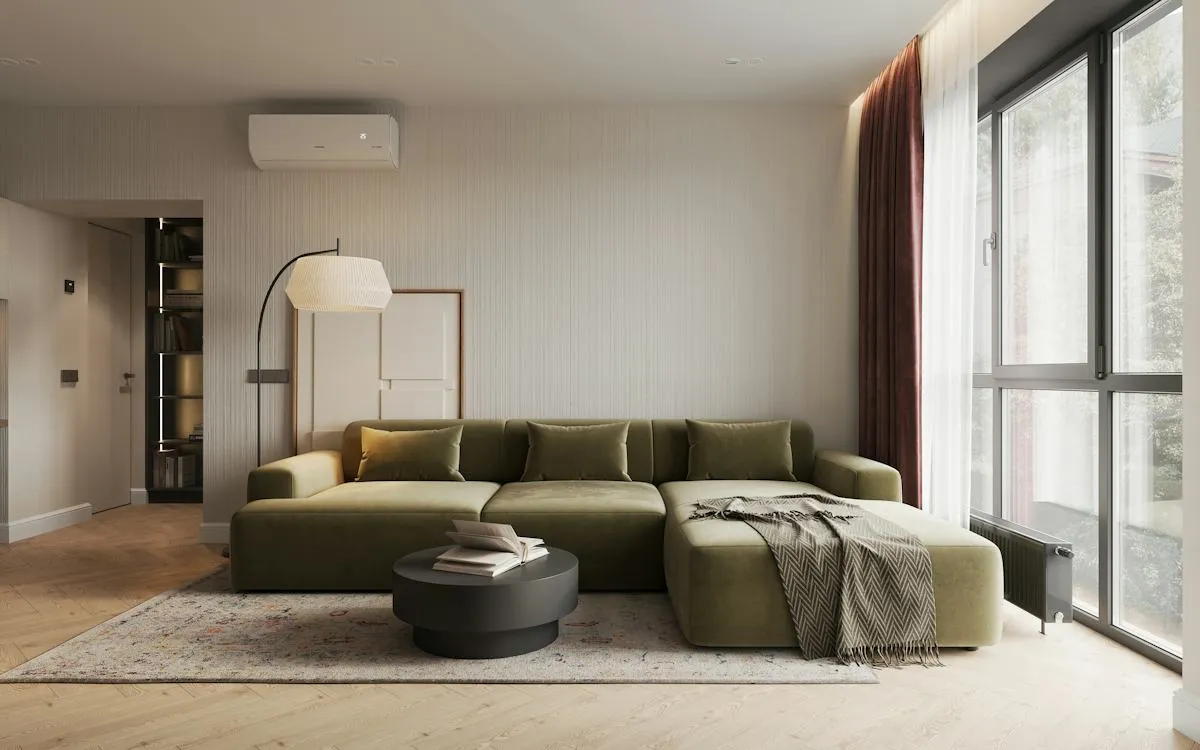 Wohnzimmer mit grünem Sofa und großen Fenstern